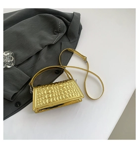 Detail of gold metallic handbag showing geometric diamond texture and top handle