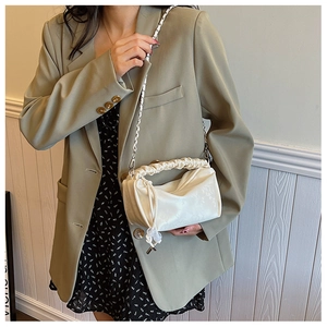 Détails de la texture satinée crémeuse et poignée plissée sur sac bandoulière élégant