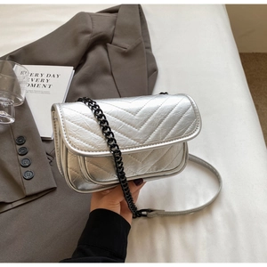 Detail view of silver quilted crossbody bag with V-shaped texture and chain strap