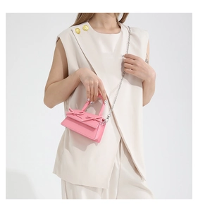 Detail of a mini pink handbag featuring double bow decor and a silver metal chain strap
