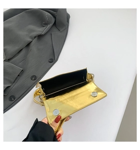 Detail of glossy gold metallic handbag with double magnetic closure and black lining