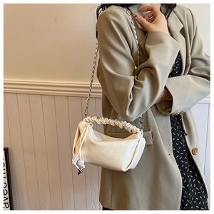 Détail du sac à main plissé crème avec texture jacquard florale et chaîne métal
