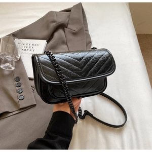 Detail of black V-quilted faux leather shoulder bag with sleek metal chain strap