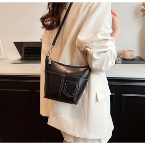 Detailaufnahme der schwarzen Ledertasche mit weißen Kontrastnähten und Silberbeschlägen