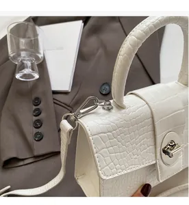 Detail of white crocodile pattern PU leather handbag with silver metallic lock and hardware