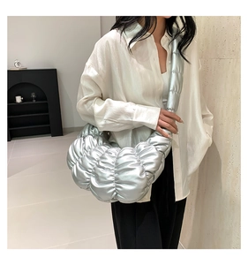 Detail of silver metallic pleated cloud bag showing glossy texture and crescent shape