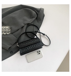Detail of black faux crocodile leather handbag with silver hardware and detachable strap
