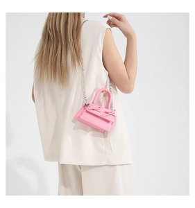 Detail of pink mini handbag with ribbon bows and silver chain strap on cream outfit