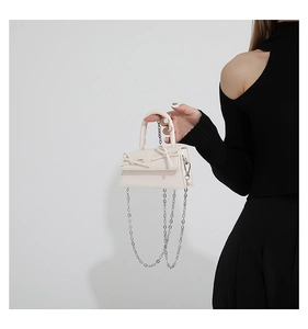 Close-up of mini cream crossbody bag featuring dual bows and silver chain strap