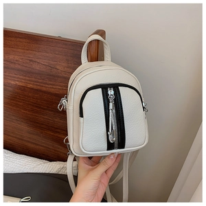 Detail eines cremeweißen Mini-Rucksacks aus strukturiertem Leder mit schwarzen Reißverschlüssen