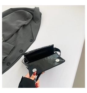 Internal view of glossy black shoulder bag with spider web texture and magnetic buckles