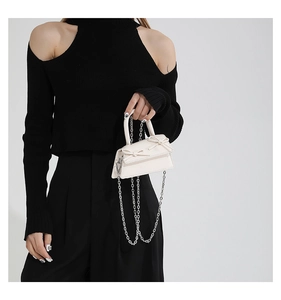 Detail of mini cream leather bag with double bow accents and silver chain strap