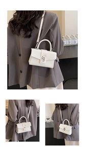 Detail of white crocodile pattern crossbody bag with silver oval turn-lock closure