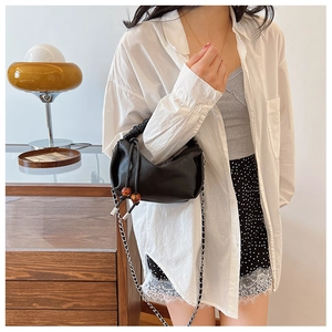 Détail du sac nuage plissé en cuir noir avec perles d'ambre et bandoulière chaîne