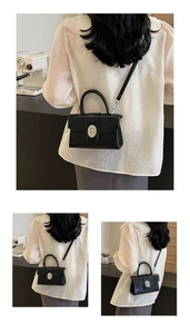 Detail view showing black crocodile textured crossbody bag with silver oval metal buckle