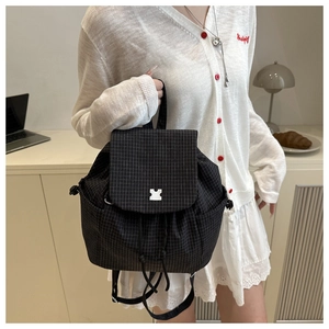 Detail of drawstring backpack with black lattice pattern and white puzzle buckle