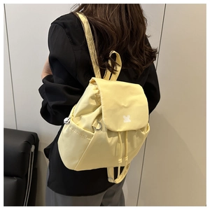 Detail of light yellow backpack with drawstring closure and flap cover on model