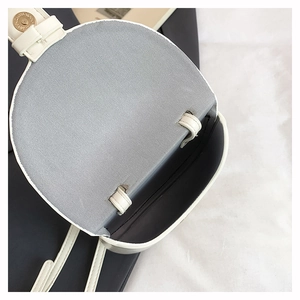 Macro detail of white round crossbody bag interior with gold magnetic buckle and grey lining