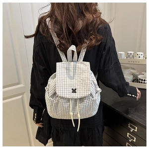 Detailed back view of a grey plaid backpack featuring a flap cover and drawstring closure