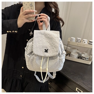 Detail of a mini black and white checkered backpack with a cross logo and drawstring closure