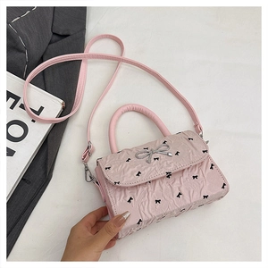 Detailed macro shot of light pink leather texture and silver bow buckle on small handbag