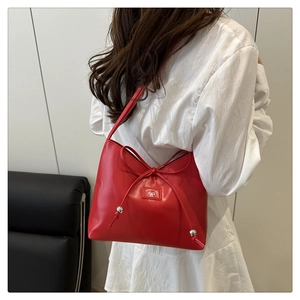 Dettaglio della borsa a spalla in pelle rossa con fiocco decorativo e logo sulla spalla