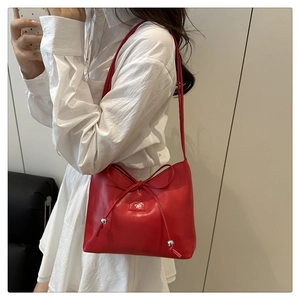 Close-up of bright red leather shoulder bag with decorative bow and silver beads