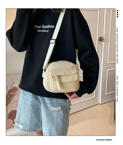 Détail d'un sac bandoulière en velours côtelé blanc cassé avec poche avant porté par un modèle