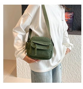 Close-up of green corduroy crossbody bag with front pocket and fabric shoulder strap