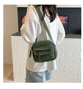 Detail of dark green corduroy crossbody bag featuring a textured strap and woven zipper puller