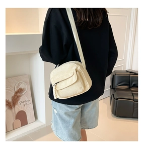 Corduroy crossbody bag detail showing zipper, texture, and model fit in minimalist room