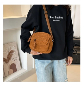 Brown corduroy crossbody bag shown on model with adjustable strap and casual retro style