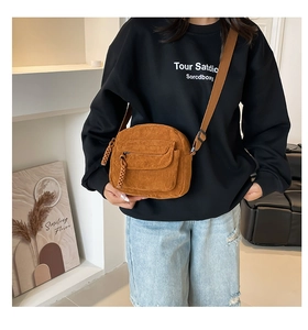 Detail of brown corduroy crossbody bag with woven zipper pull and adjustable strap