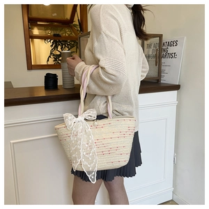 Close-up of woven tote bag with red dots, pearl button and a large white lace bow