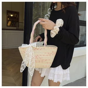 Close-up of handmade straw tote bag with colorful dots and white lace bow decoration