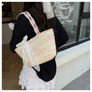 Detail of straw woven bag with lace bow, pearl button, and colorful rope handles