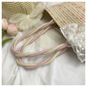 Detail of hand-woven beige tote bag with floral embroidery and white lace bow detail