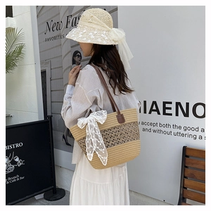 Detail of straw woven tote bag with white lace bow and matching straw hat for beach vacation