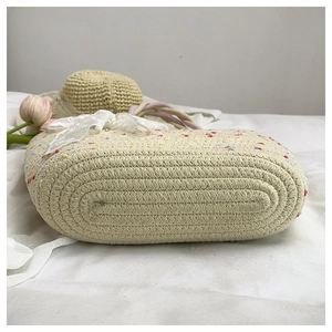 Detail of hand-woven straw basket bag bottom showing tight spiral beige weaving texture