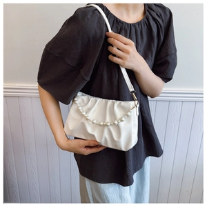 Detail of white pleated cloud bag featuring pearl chain strap and PU leather texture