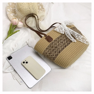 Straw tote bag with delicate white lace bow and brown leather straps for summer travel
