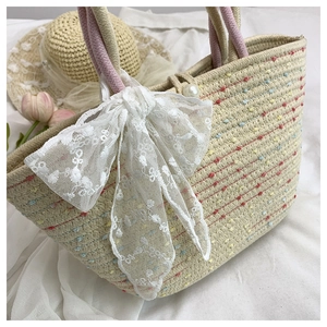 Detail of hand-woven tote bag featuring lace bow, colorful polka dots, and pearl closure