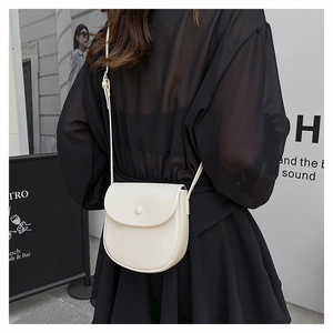 Detail of a vintage-style cream saddle bag featuring a minimalist flap and round buckle