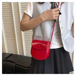 Detailed view of the red saddle bag worn cross-body over a stylish grey vest and white shirt
