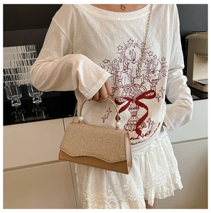 Détail du sac à main à paillettes avec poignée en métal doré, perles et chaînette