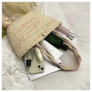 Detail view of large capacity hand-woven straw bag with pearl clasp showing interior storage