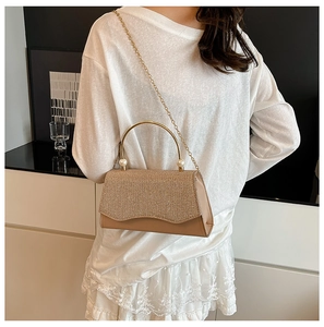 Détail du sac de soirée pailleté champagne doré avec poignée anneau et perles sur robe