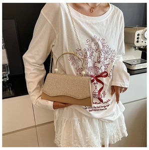 Détail du sac à main carré doré pailleté avec poignée métallique et perles chic