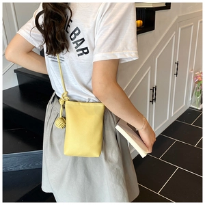 Detail of lemon yellow crossbody phone bag with pebble leather texture and knotted strap