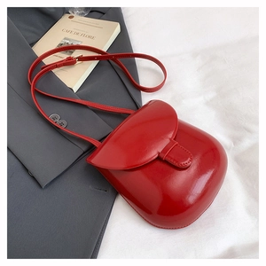 Chic red patent leather crossbody bag displayed on a grey blazer for a French vintage vibe